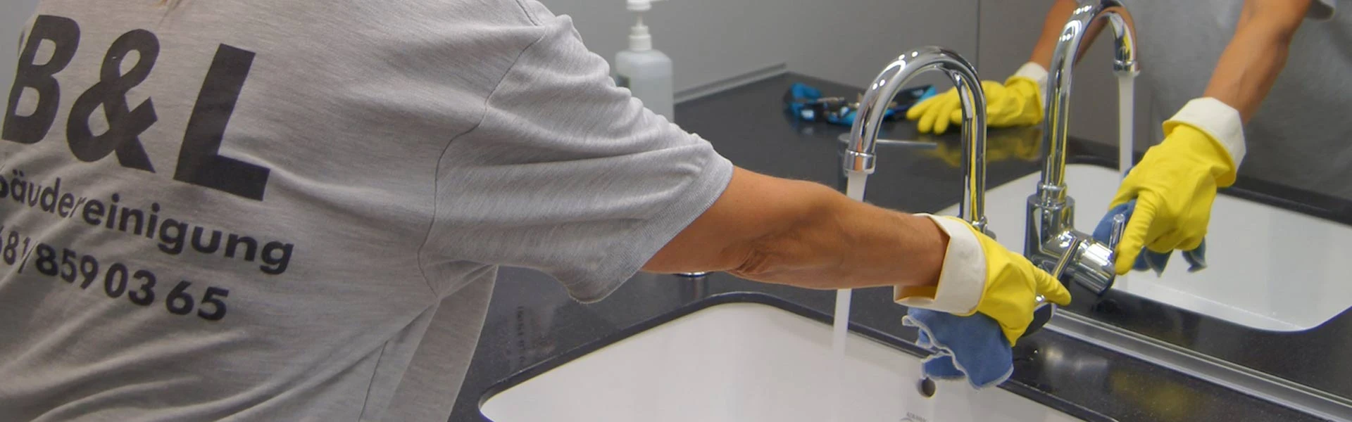 Frau putzt ein Waschbecken dessen Wasserhahn läuft